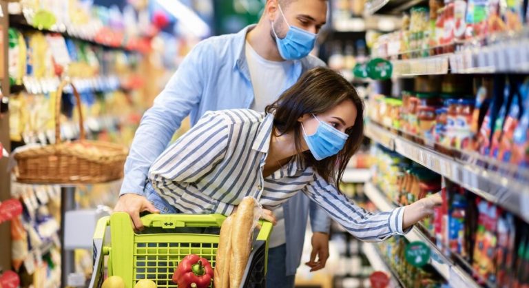 Young couple in protective masks shopping in supermarket